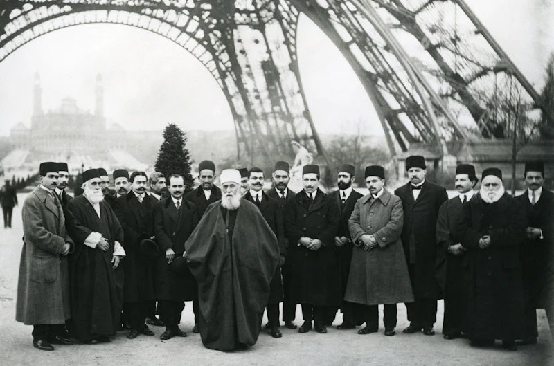Abdu’l-Bahá and His Travel companions standing beneath the Eiffel Tower