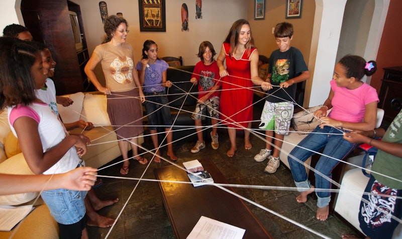 A circle of children playing a 'getting acquainted' game with a rope